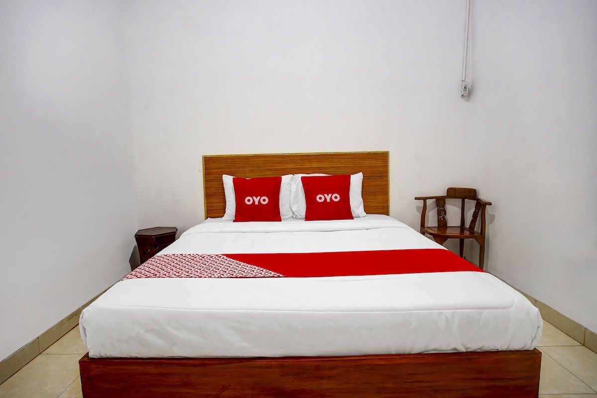 A neatly made bed with a wooden headboard, two red and white pillows, and a red and white bedspread.