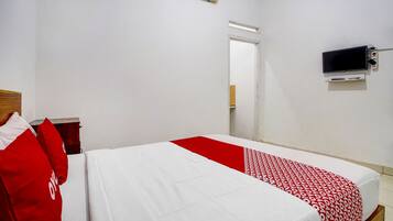 A hotel room with a bed, a TV mounted on the wall, and a door leading to another room.