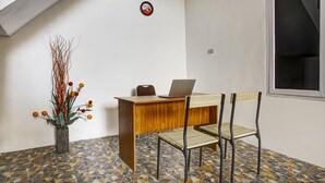 A room with a wooden desk, two chairs, a laptop, and a vase with dried branches. - OYO Life 91068 Penginapan Way Semaka Syariah (Bandar Lampung)