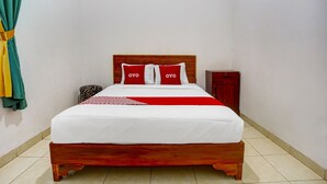 A neatly made bed with a wooden frame, two pillows with 'OYO' branding, and a red and white bedspread. - OYO Life 91068 Penginapan Way Semaka Syariah (Bandar Lampung)
