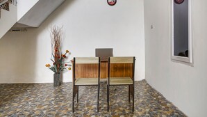 A room with a tiled floor, two wooden chairs, a small potted plant, and a wooden desk. - OYO Life 91068 Penginapan Way Semaka Syariah (Bandar Lampung)