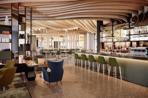 Zona de bar moderna con techo curvo, taburetes y una barra larga con botellas.