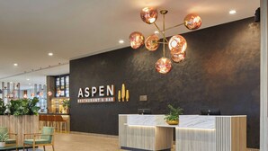 A reception area with a dark wall, a sign reading 'ASPEN RESTAURANT & BAR', and a modern chandelier. - Courtyard By Marriott Sheffield (Sheffield)