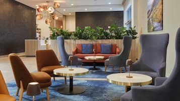 A modern lounge area with seating, tables, and a decorative ceiling light fixture.