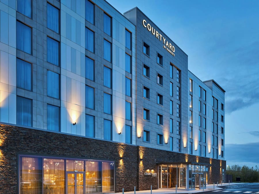 A Courtyard by Marriott hotel with a modern facade, large windows, and a well-lit entrance.
