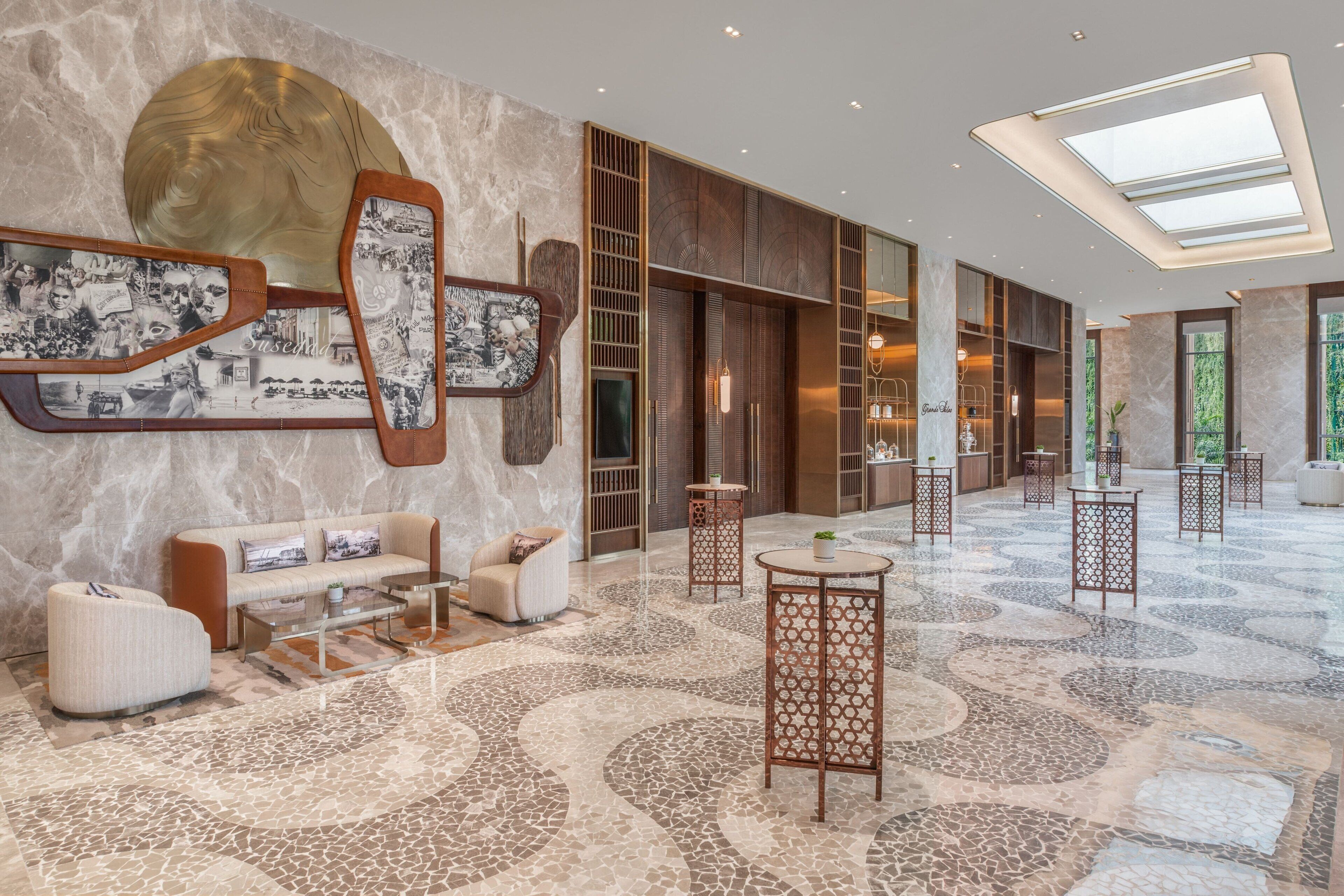 A spacious lobby with a marble floor, a sofa, a coffee table, and a large wall art piece.