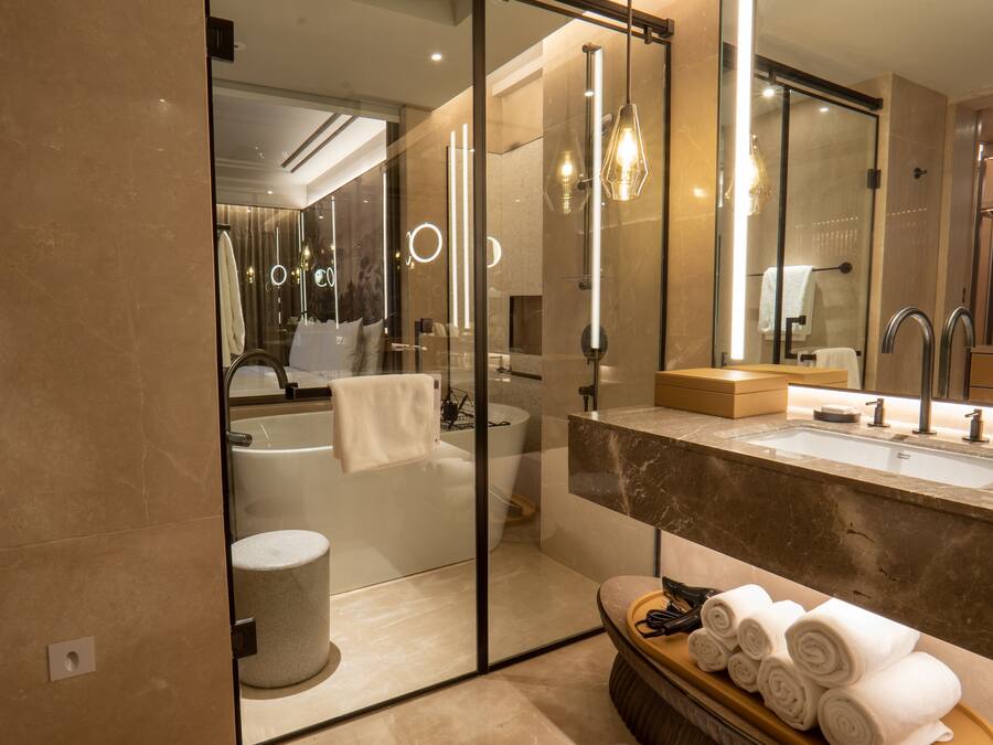 Un baño moderno con ducha de vidrio, una bañera, tocador con lavamanos y un espejo.