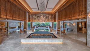 A spacious lobby with a central water feature, wooden paneling, and a chandelier.