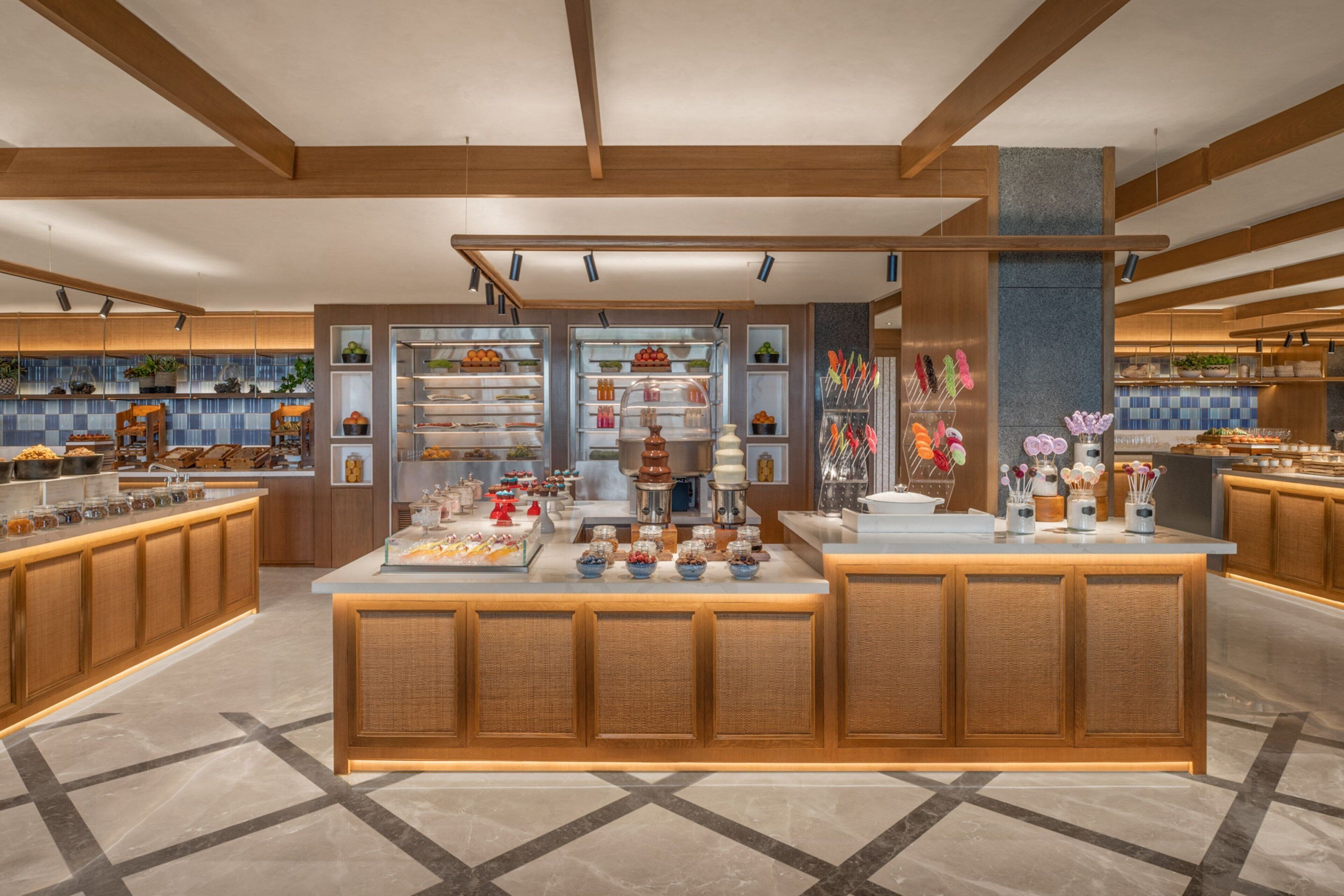 A modern kitchen with wooden cabinets, a central island with food displays, and a tiled backsplash.