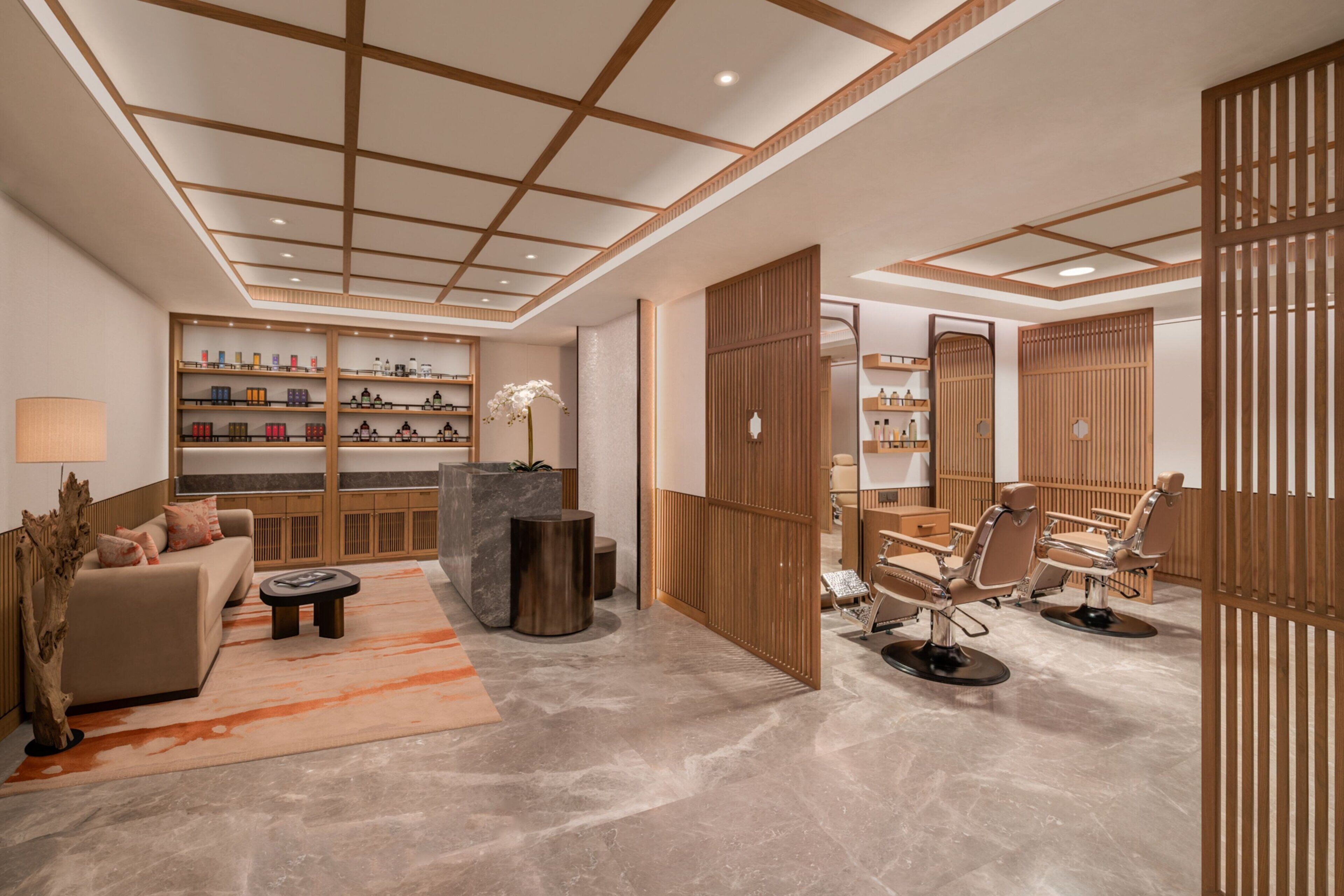 A modern interior with a sofa, coffee table, and chairs, a reception desk, and a wooden partition.