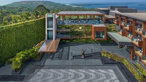 A modern hotel with a rooftop pool, lush greenery, and a scenic ocean view.