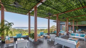 A covered outdoor seating area with modern furniture and a view of the landscape.