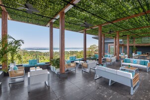 Un espacio de estar al aire libre con techo, mobiliario moderno y vista al paisaje.