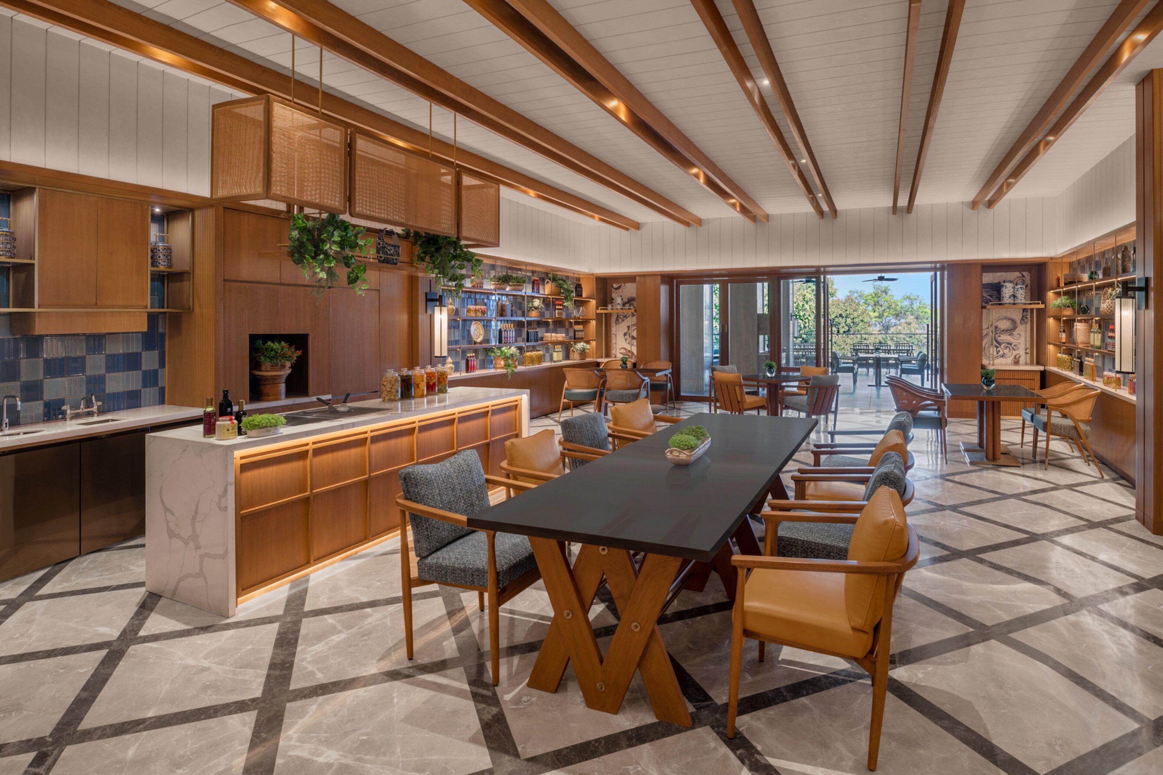 A modern kitchen with wooden cabinetry, a central island, and a dining area with chairs and a table.
