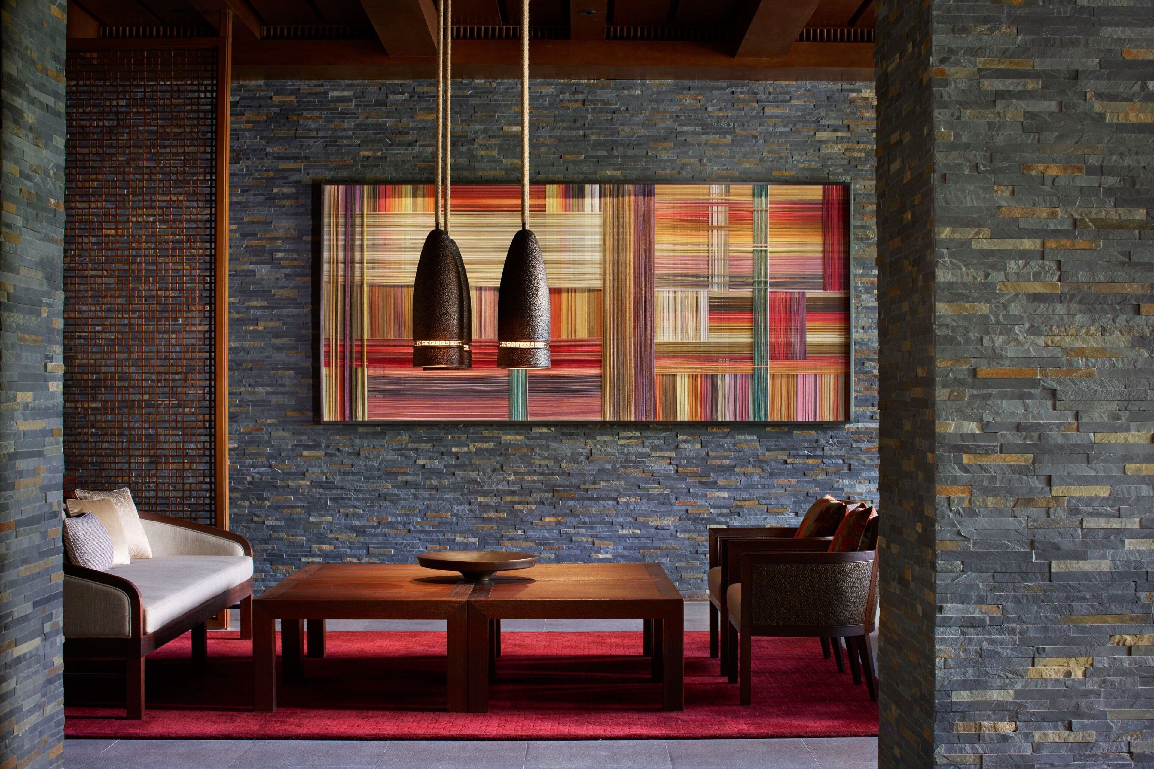 A modern interior with a brick wall, a large abstract painting, a wooden table, and two chairs.