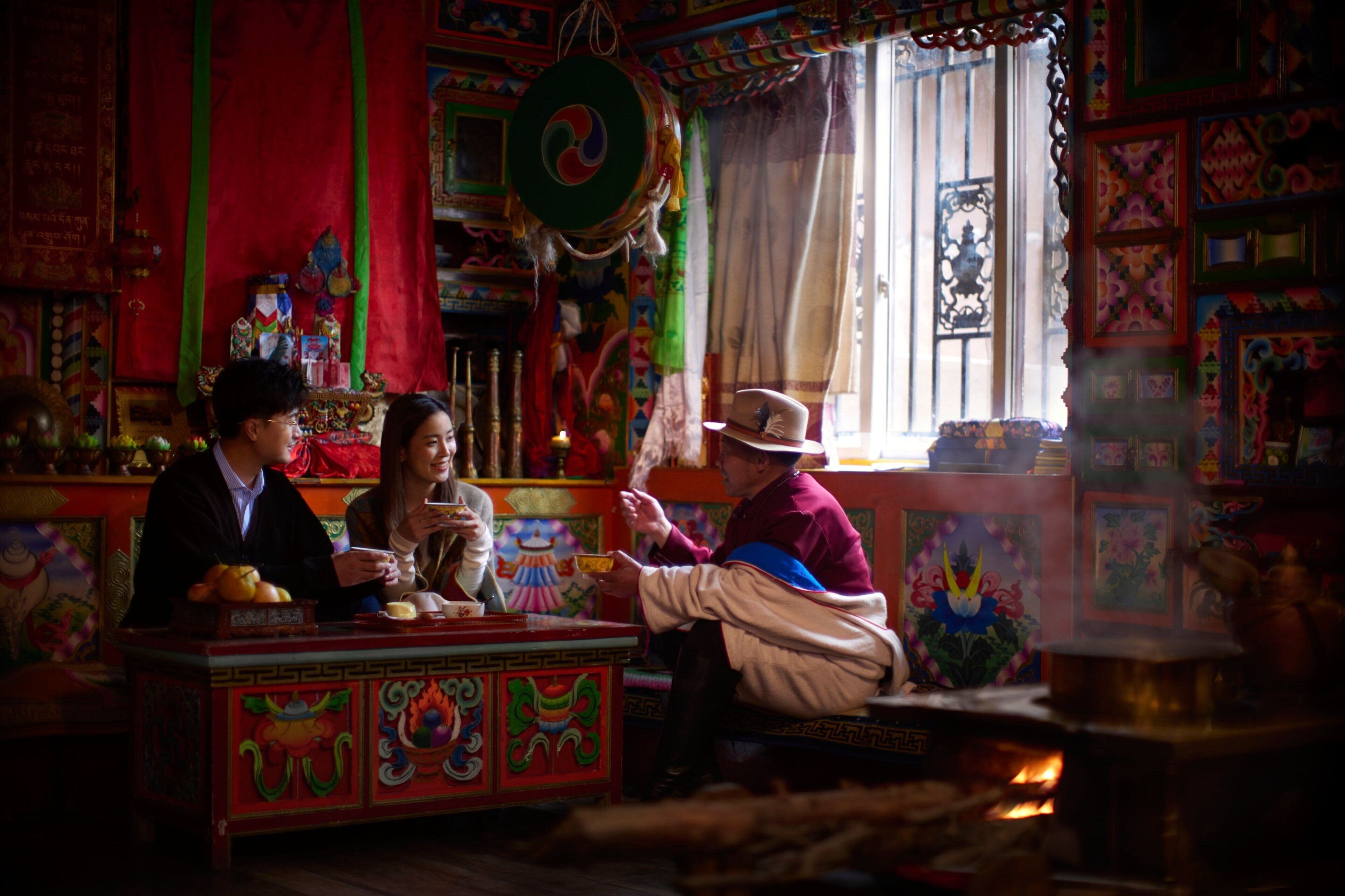 A traditional room with colorful decorations, a prayer wheel, and a fire.