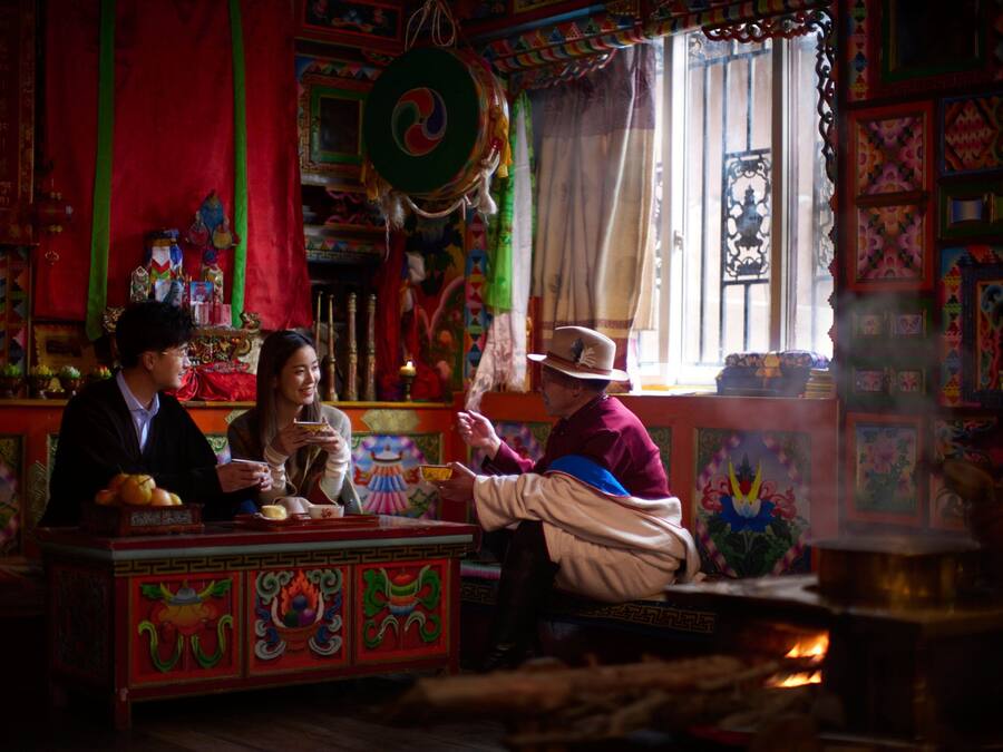 A traditional room with colorful decorations, a prayer wheel, and a fire.