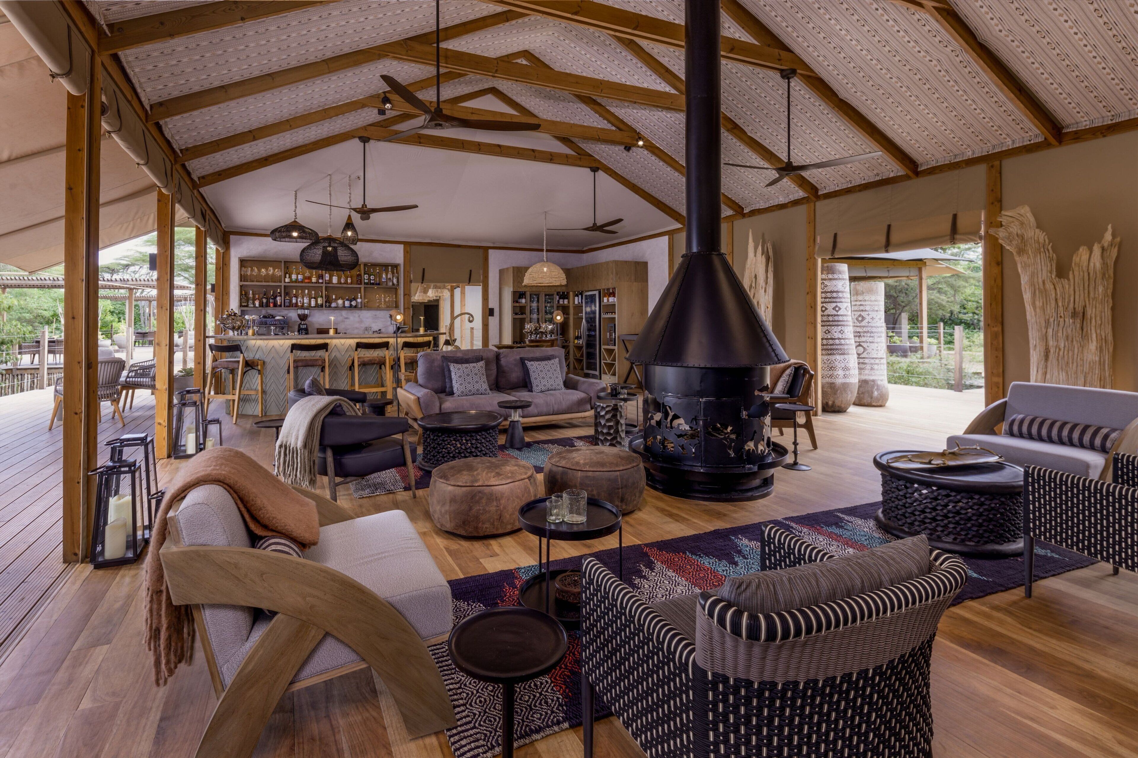Amplia sala de estar con chimenea, muebles de madera y una zona de bar al fondo.