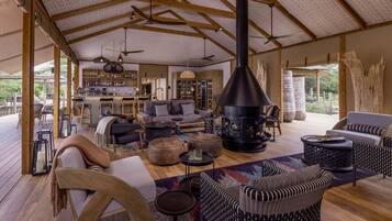 Amplia sala de estar con chimenea, muebles de madera y una zona de bar al fondo.