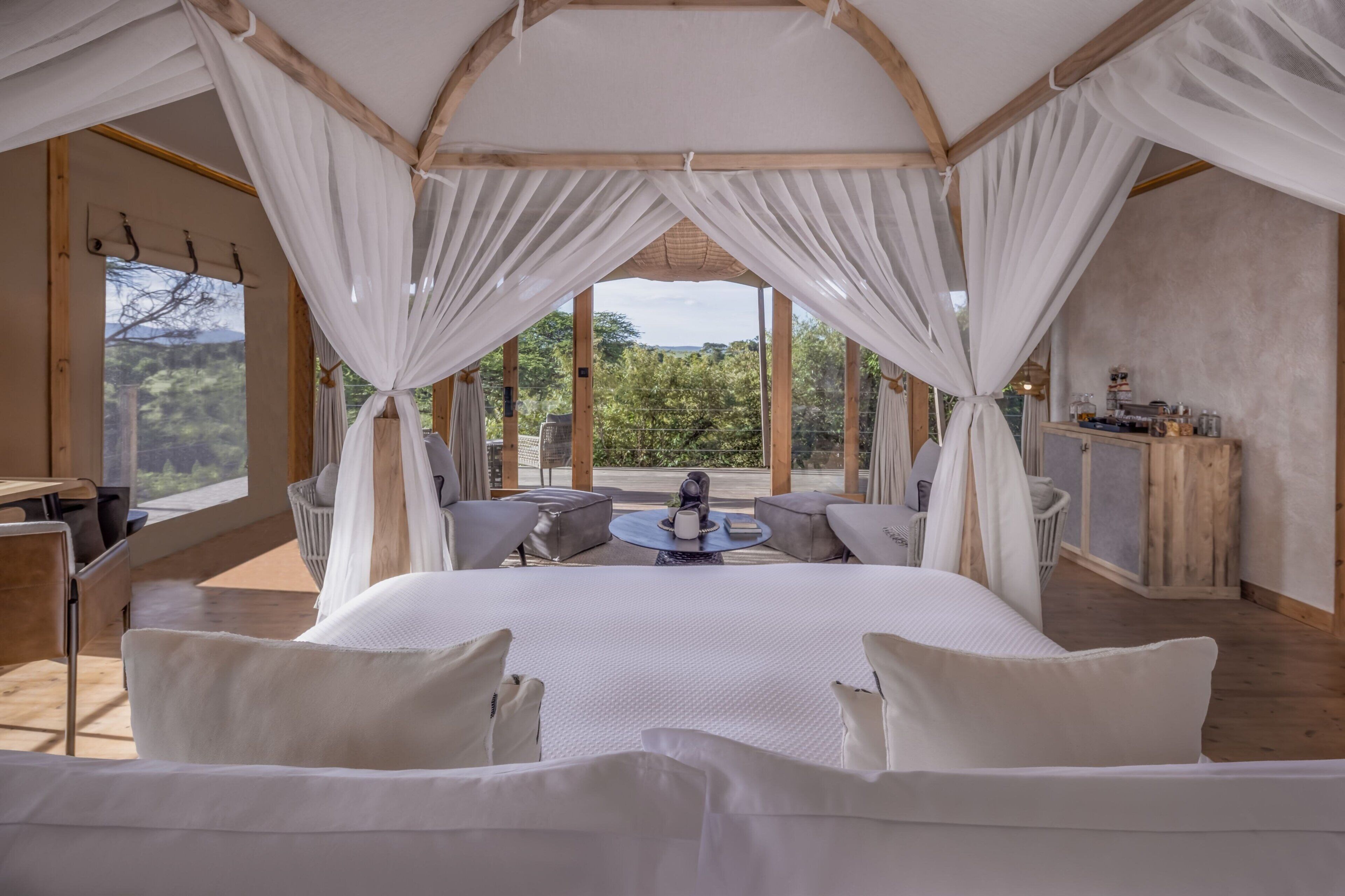 Ein geräumiges Schlafzimmer mit einem großen Bett, einer Sitzecke mit Tisch und Blick ins Freie.