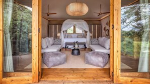 A cozy room with a bed, two sofas, a coffee table, and a large window.