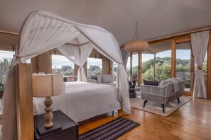 Un dormitorio con cama de dosel, un sofá y vistas al exterior.