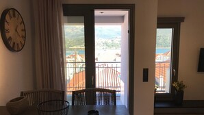 Una stanza con un tavolo, sedie, un orologio e vista su un balcone con edifici.