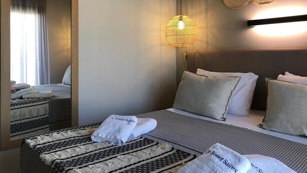 Una camera d'albergo con un letto grande, un comodino, uno specchio e una lampada a parete.