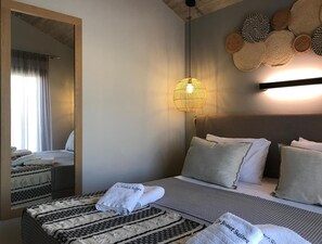 A hotel room with a large bed, a bedside table, a mirror, and a wall-mounted light fixture. - Superior Suite With sea Views to Argostoli bay (Kefalonia)