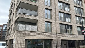 A multi-story residential building with balconies, large windows, and a visible parking area. - Remarkable 2-bedroom Apartment Near Kings Cross (London)