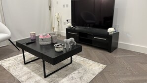 A modern living room with a black coffee table, a flat-screen TV, and a grey sofa. - Remarkable 2-bedroom Apartment Near Kings Cross (London)