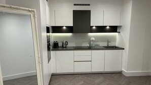 A modern kitchen with white cabinets, a black countertop, and a herringbone-patterned floor. - Remarkable 2-bedroom Apartment Near Kings Cross (London)