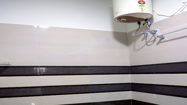 A bathroom with a toilet, a shower, and a water heater. - Golden Residency (Vanur)