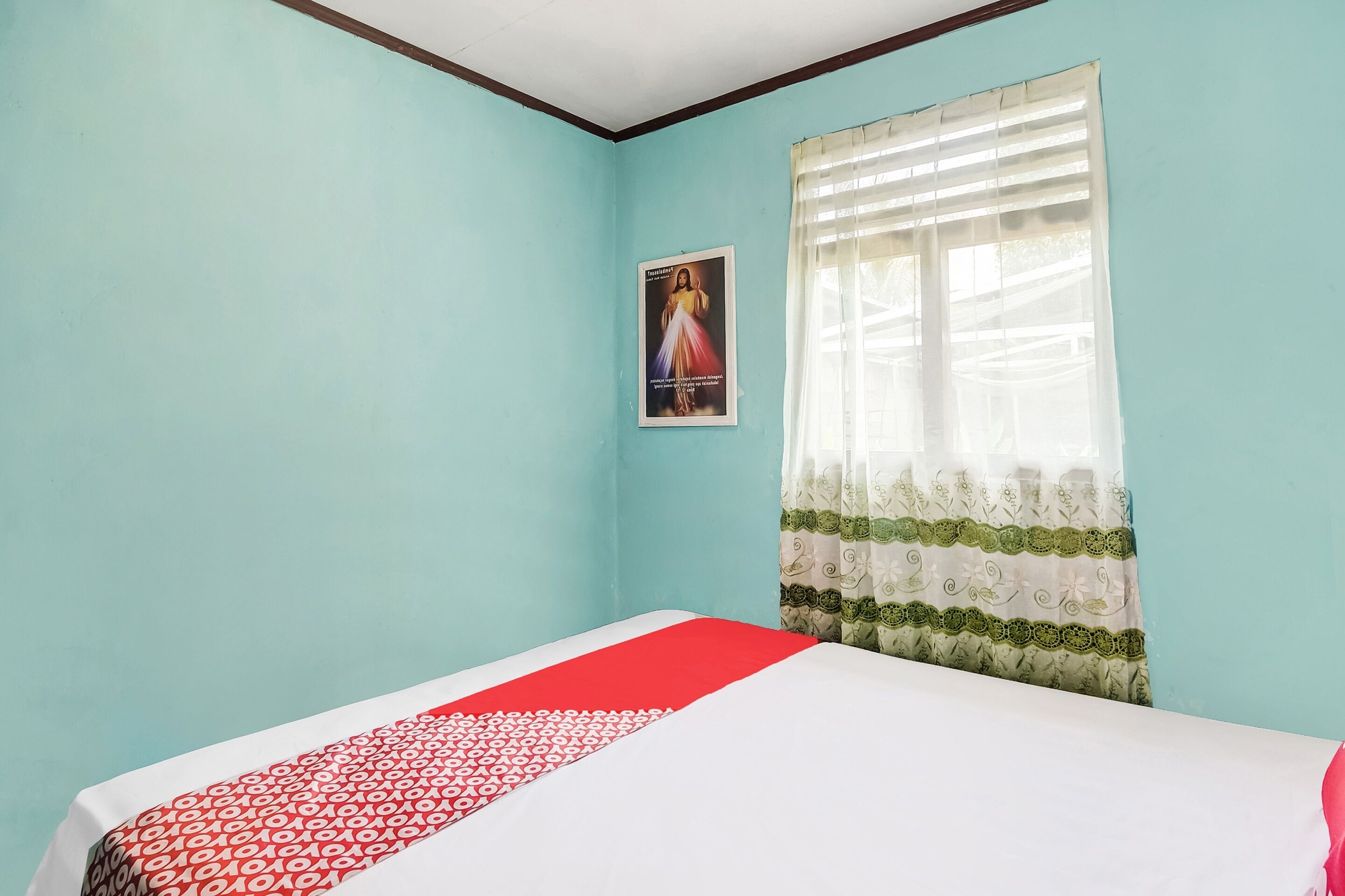 Une chambre à coucher avec un lit, une fenêtre ornée de rideaux légers et une affiche accrochée au mur.