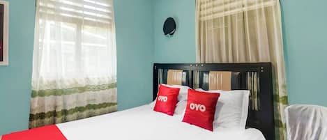 A neatly made bed with white and red bedding, a headboard, and two pillows with the word "OYO" on them.