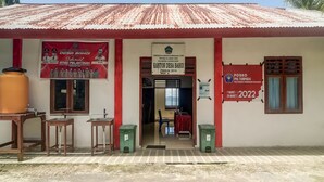 A building with a corrugated metal roof, a signboard for Desa Bahoi, and a POSKO PHL TEPADU sign. - OYO Homes 91148 Homesstay Desa Wisata Bahoi Near Ekowisata Mangrove Desa Bahoi (Bahoi)