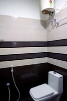 Un baño con inodoro, ducha y un calentador instalado en la pared.