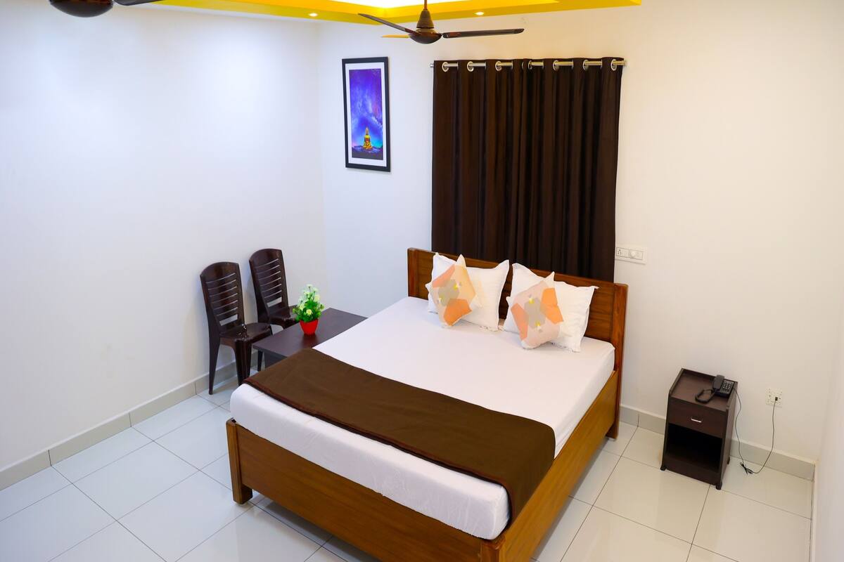 Une chambre à coucher comprenant un lit, une table de chevet, une commode, un ventilateur de plafond et un tableau encadré accroché au mur.