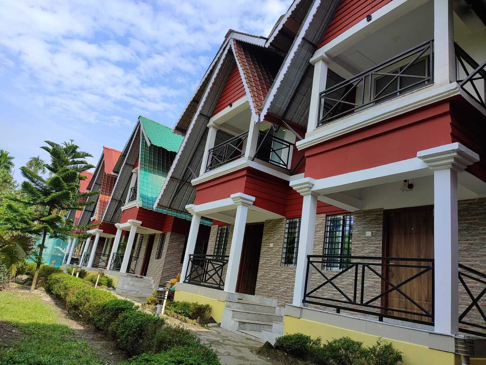 A row of multi-story buildings with red and green roofs, white columns, and balconies.