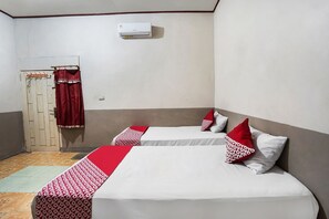 A room with two beds, a red and white patterned bed runner, a white air conditioner, and a door with a red curtain. - Hotel O Penginapan Indah Permai Syariah (Belitang)