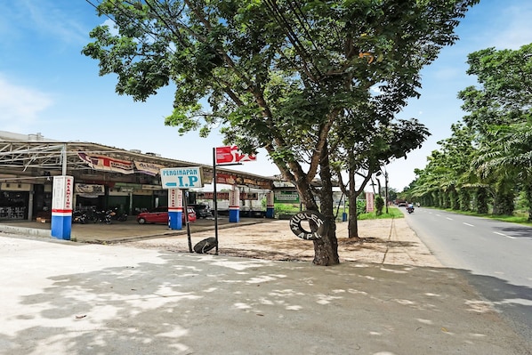 A street scene with a gas station, a tree, and a road.