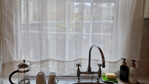 A kitchen with a window, a sink, a kettle, and two soap dispensers. - Charming Studio Sleeps 2 - Kentish Town Nwlondon (London)