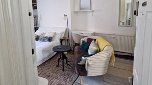 A compact hotel room with a bed, a small desk, a chair, and a sofa. - Charming Studio Sleeps 2 - Kentish Town Nwlondon (London)