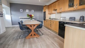 A modern kitchen with wooden cabinets, a dishwasher, and a dining area with a table and chairs.