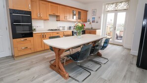 A modern kitchen with wooden cabinets, a black oven, and a dining table with chairs.