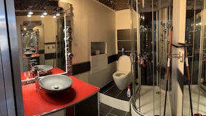 Une salle de bain moderne avec une douche à parois de verre, un lavabo rouge et des toilettes blanches.