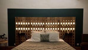 A bedroom with a large bed, a wooden headboard with circular lights, and a green wall. - La Paillère (Mus)