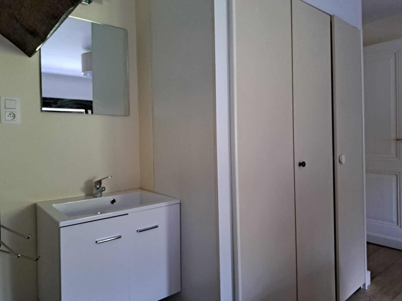 Een badkamer met een wit wastafel, spiegel en twee deuren.