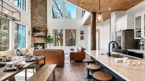 Une cuisine moderne dotée d’un grand îlot central, de planchers en bois et d’une cheminée en pierre.