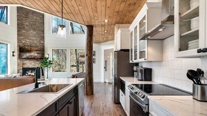 Une cuisine moderne dotée d’un grand îlot central, d’un plafond en bois et d’une cheminée en pierre.